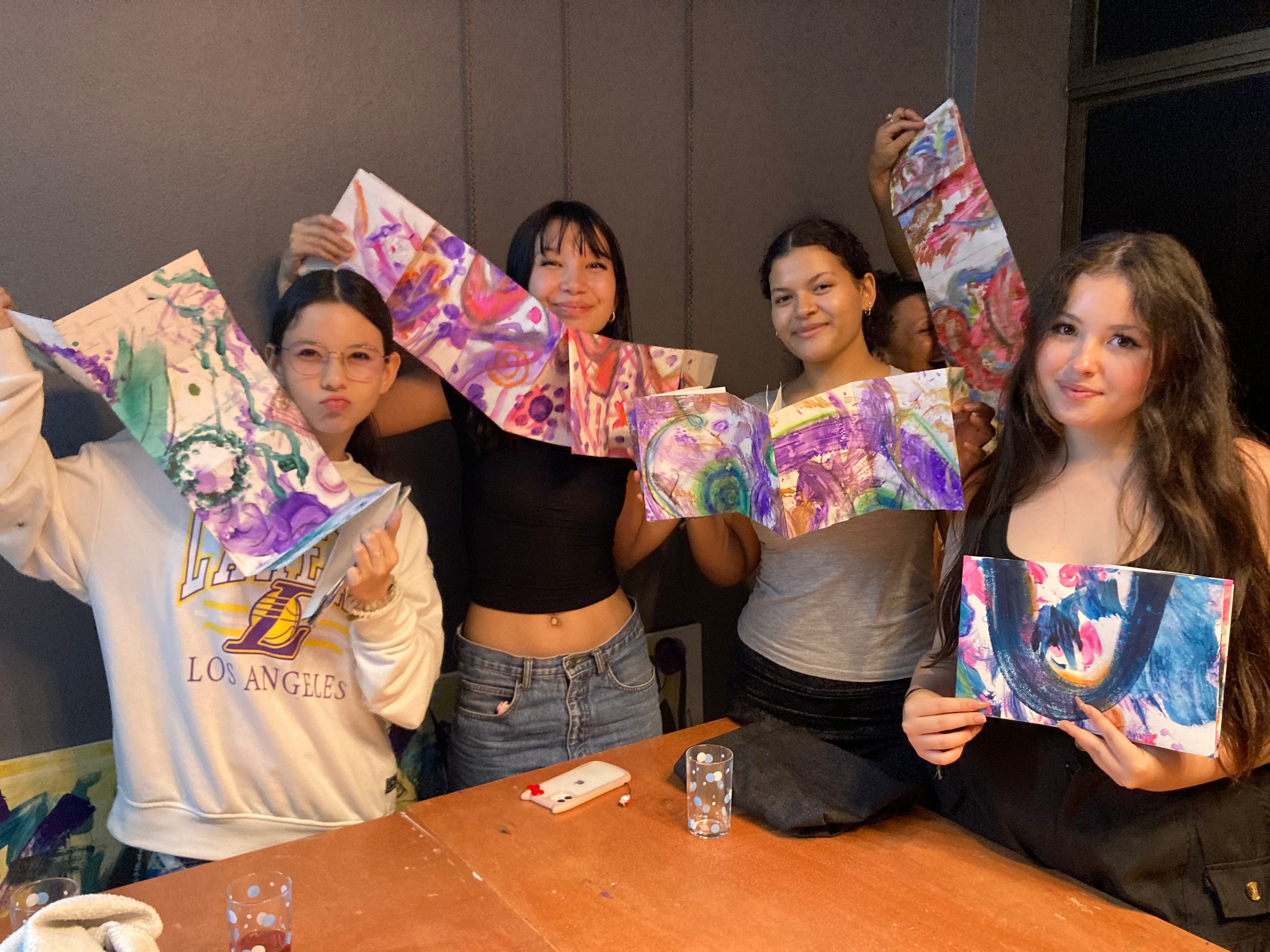 Four teens holding up their paintings
